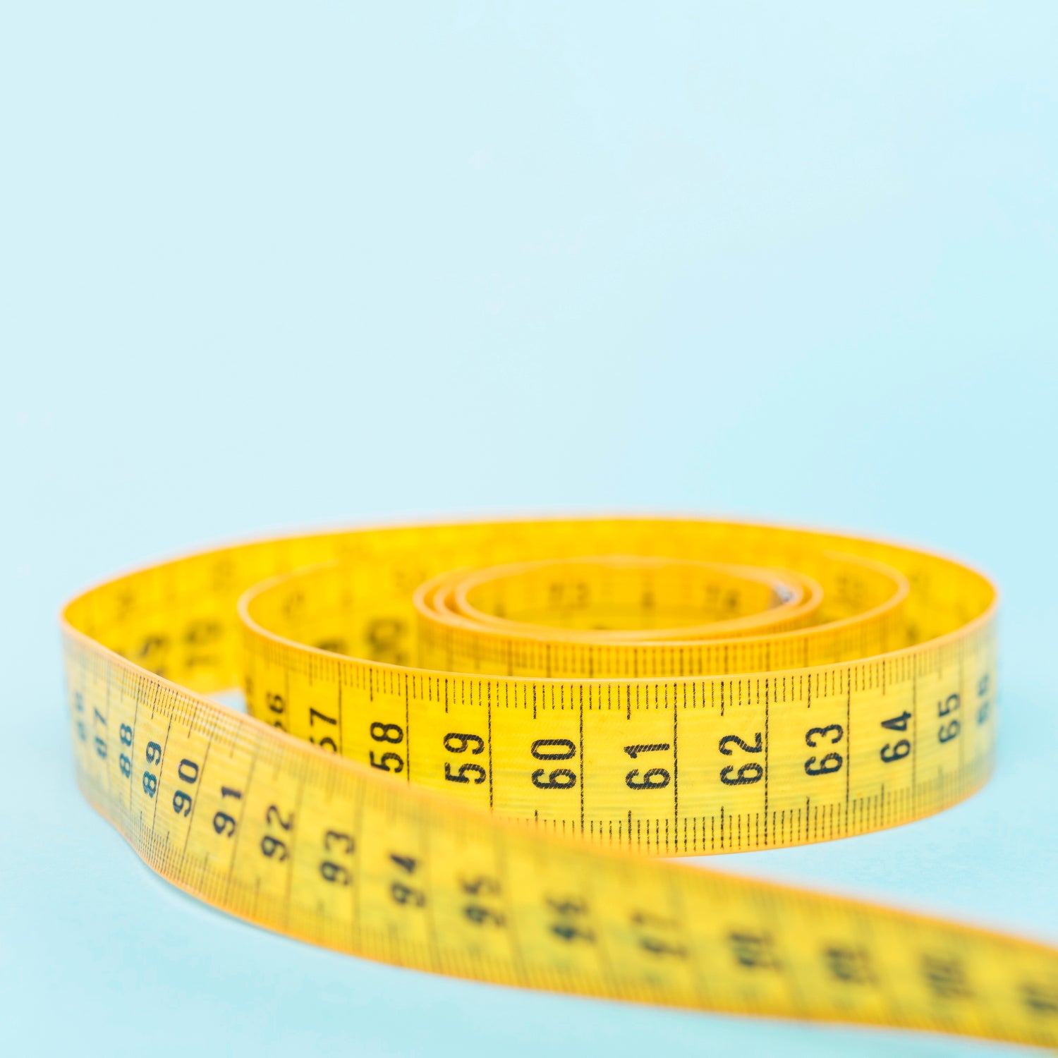 Yellow measuring tape on a light blue background